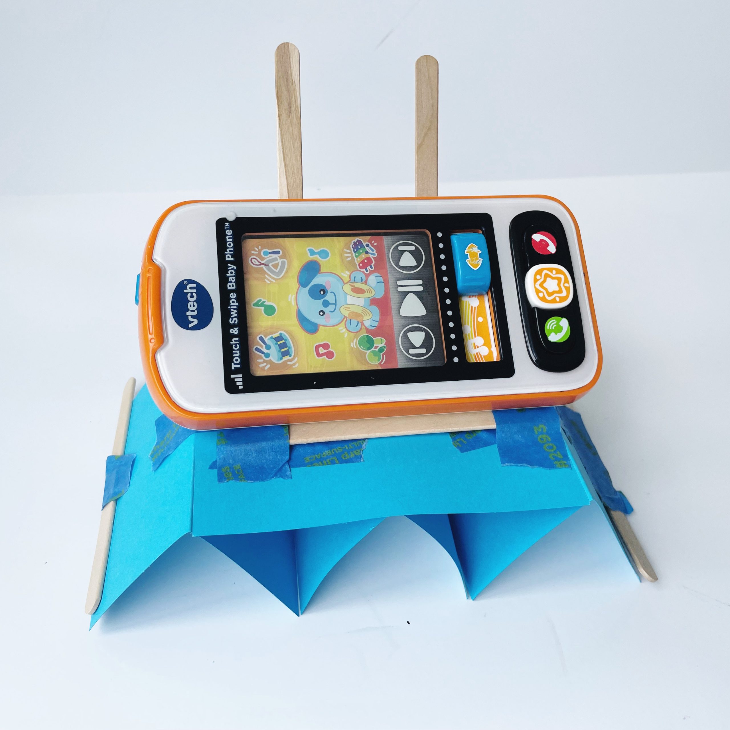 Vtech phone device on complete handmade phone stand for engineering design project as part of a what is engineering lesson